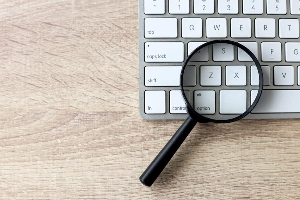 Magnifying glass on a white keyboard. Web search and SEO concept