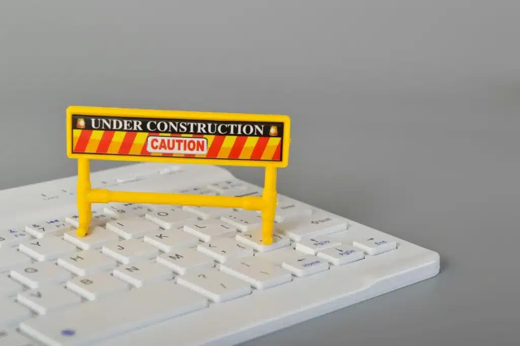 Laptop keyboard and under construction sign. Website maintenance, programming, repair, coding.