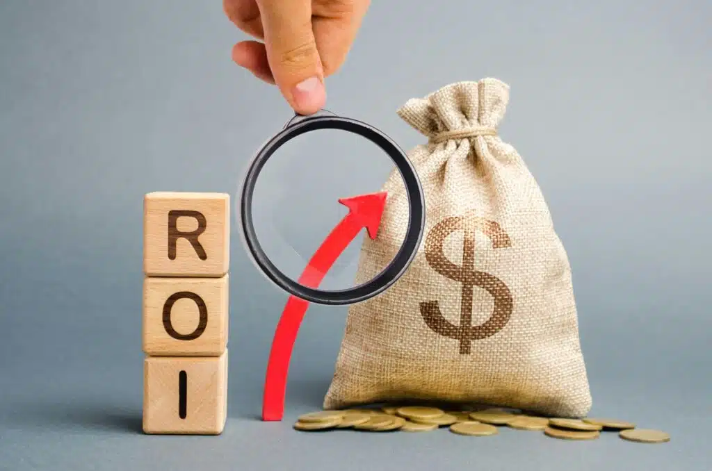 Wooden blocks with the word ROI and the up arrow with the money bag