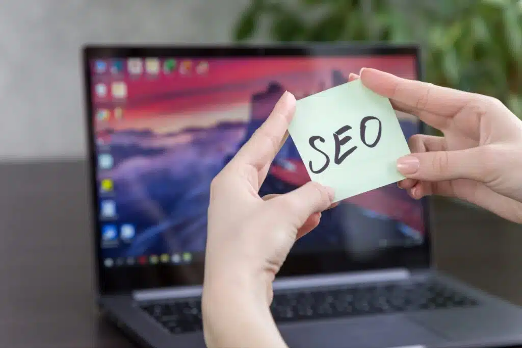 sticker with the inscription SEO in female hands on the background of a laptop